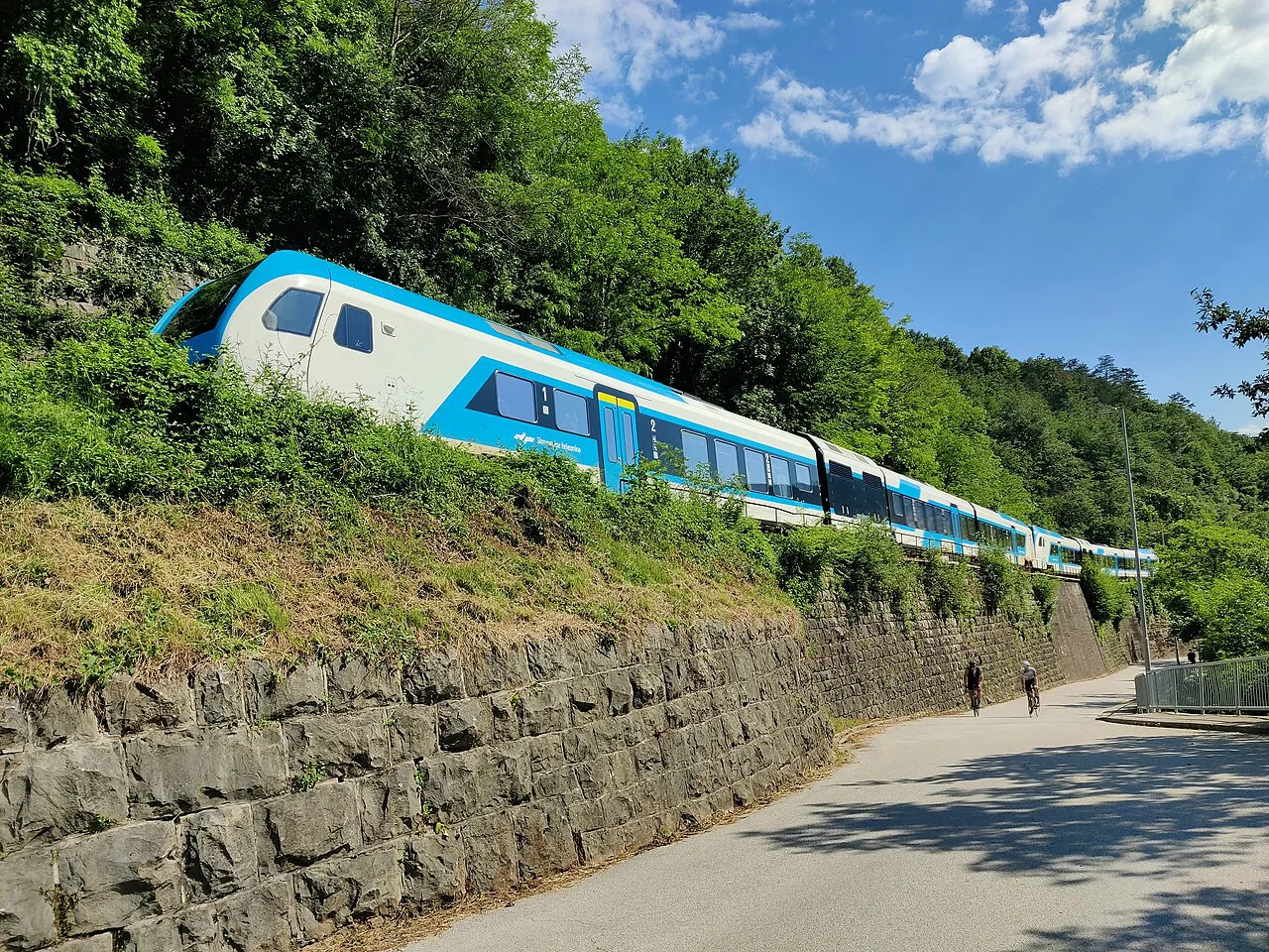 A train on the Bohinj Railway above the road.