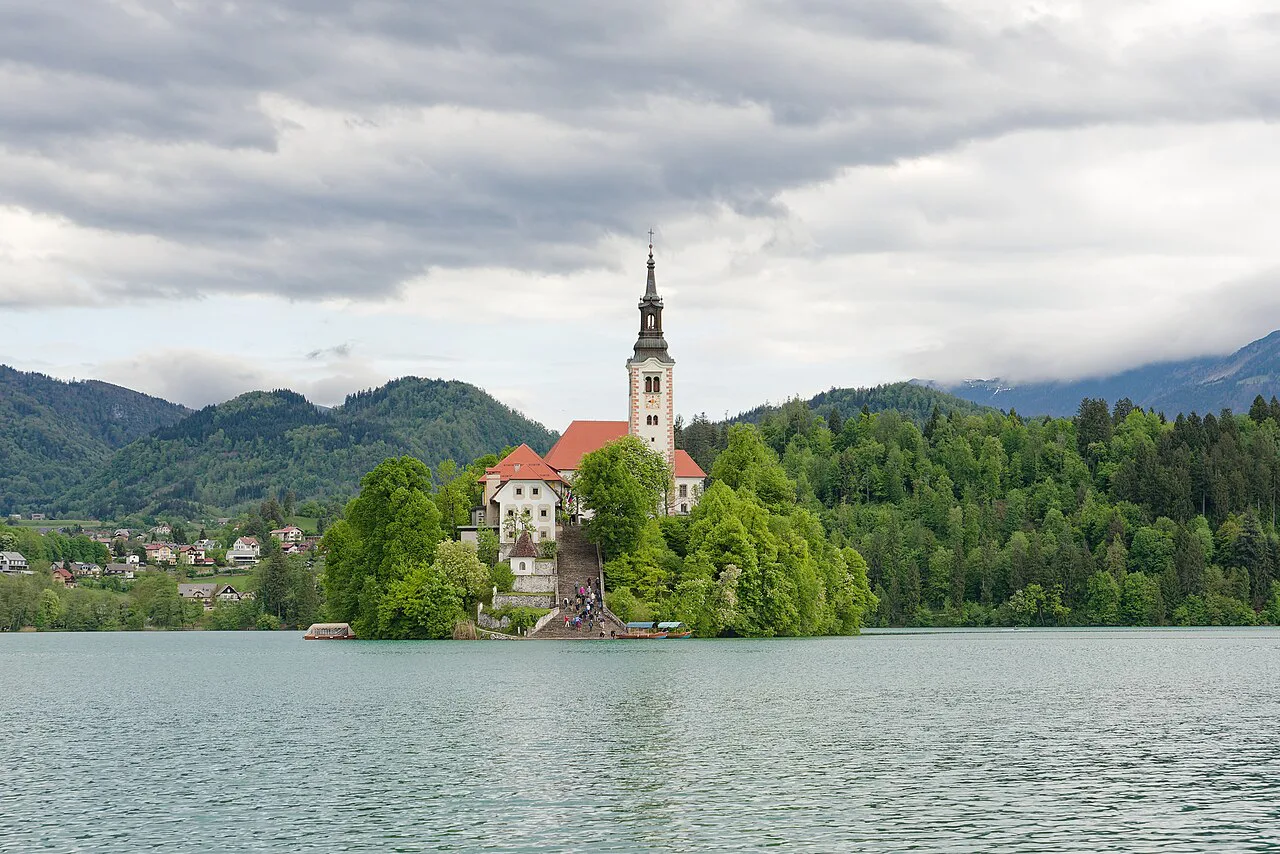 The pilgrimage church on Bled Island under a cloudy sky.