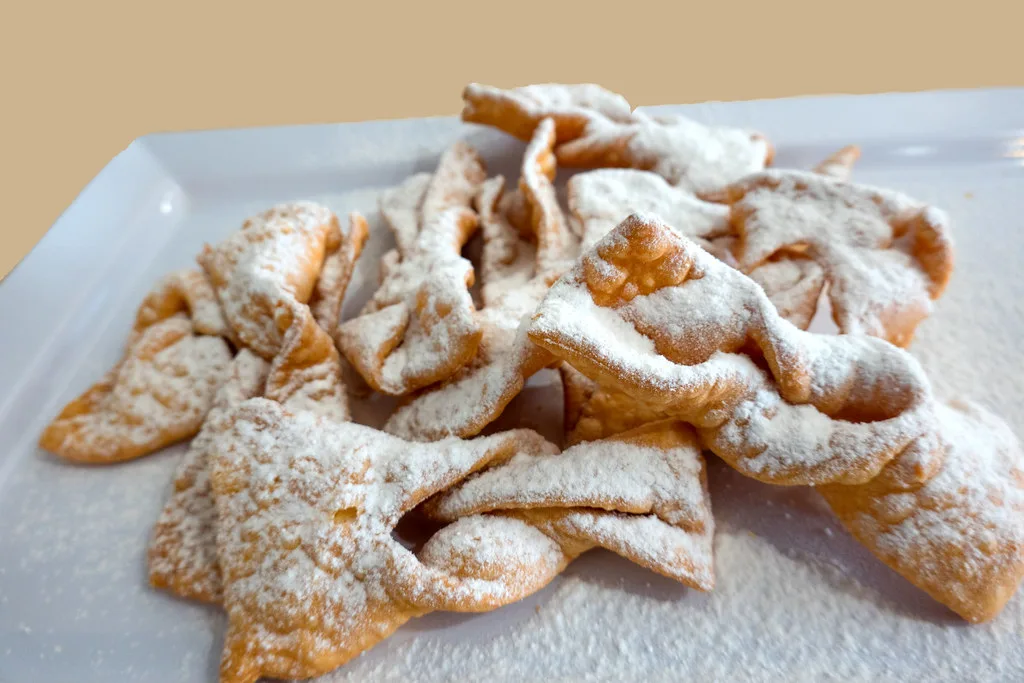 A plate of angel-wing pastries like flancati.