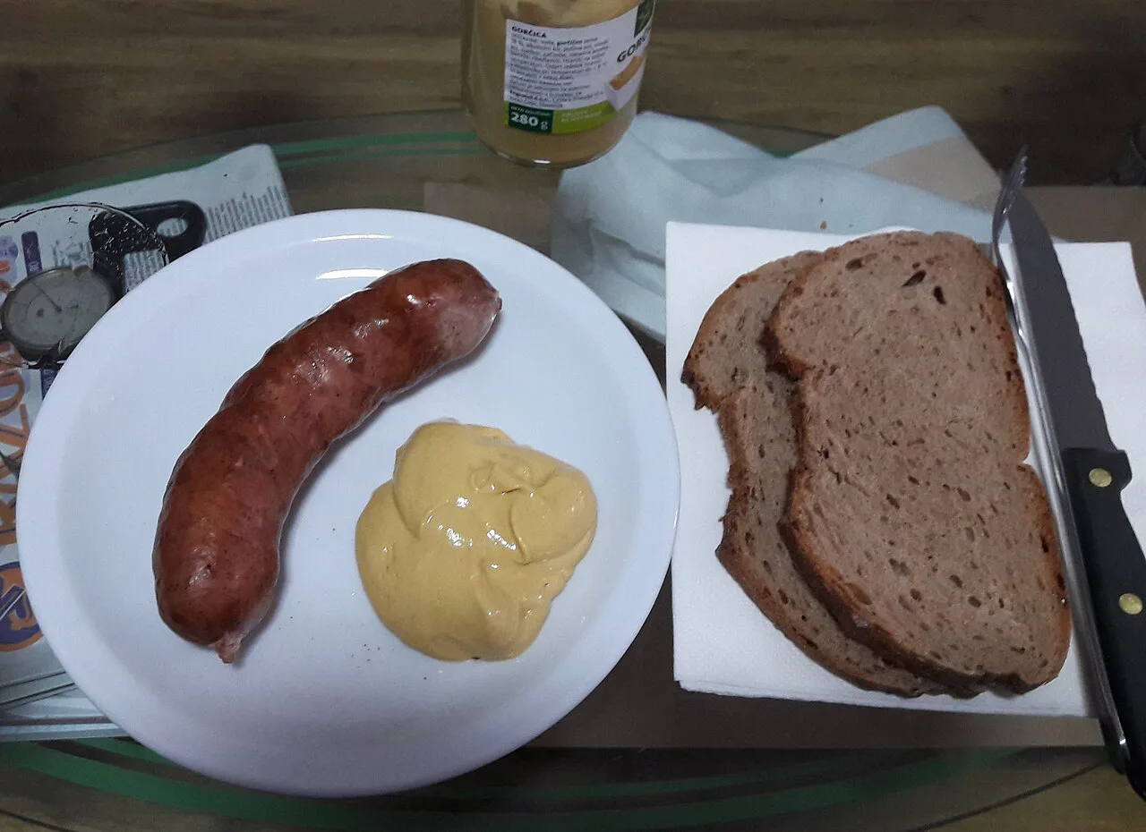Kranjska klobasa with mustard and bread.