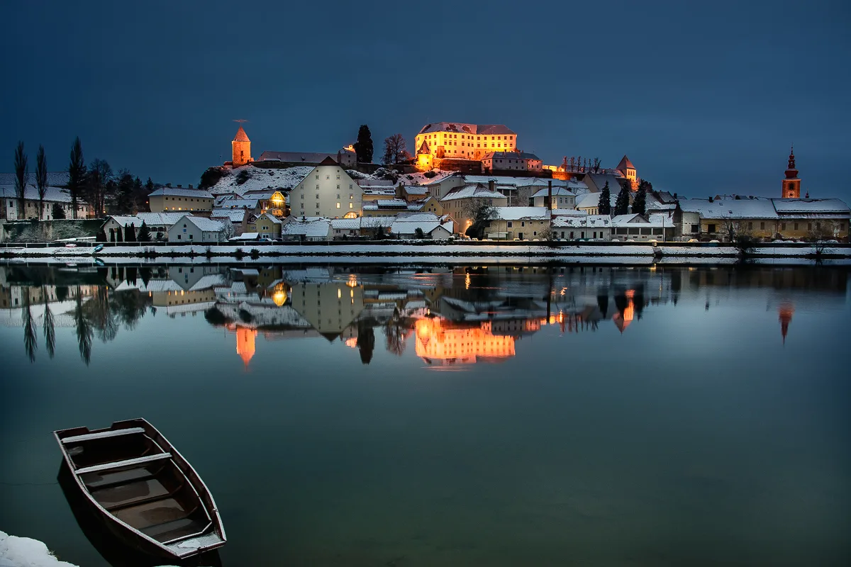 Ptuj Castle lit at dawn above the Drava.